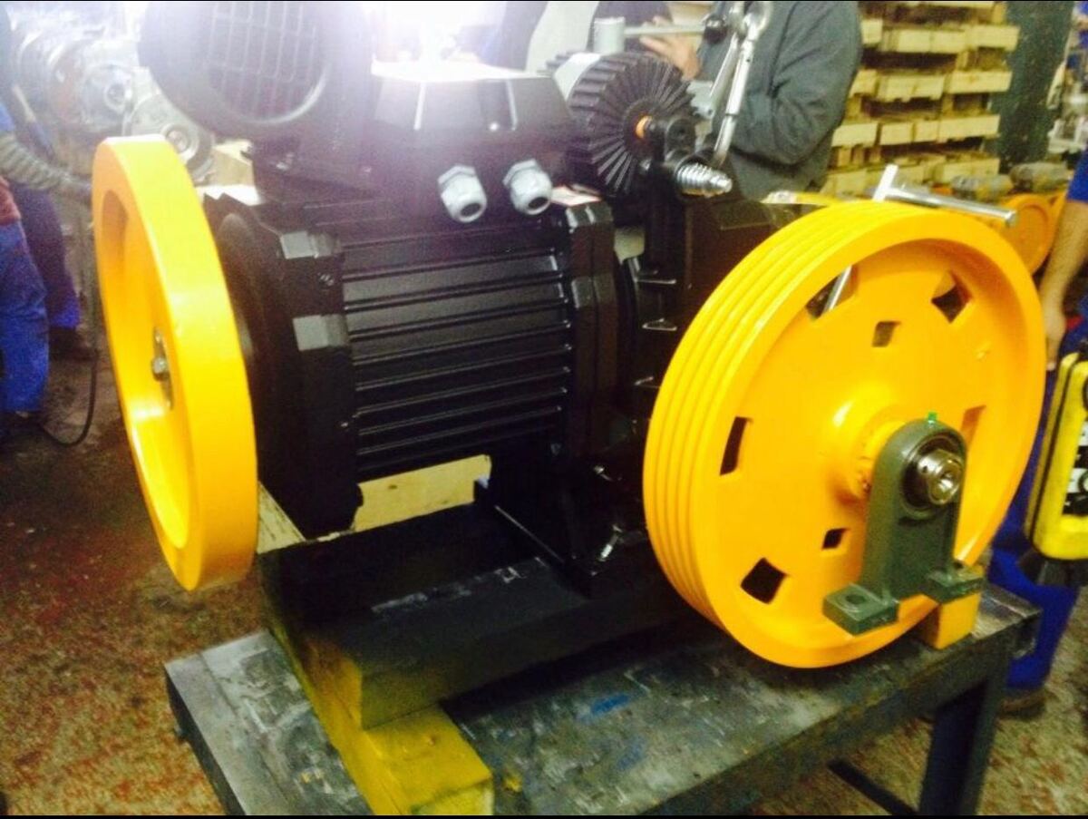 Elevator machine fitted with yellow traction sheaves on a workshop bench